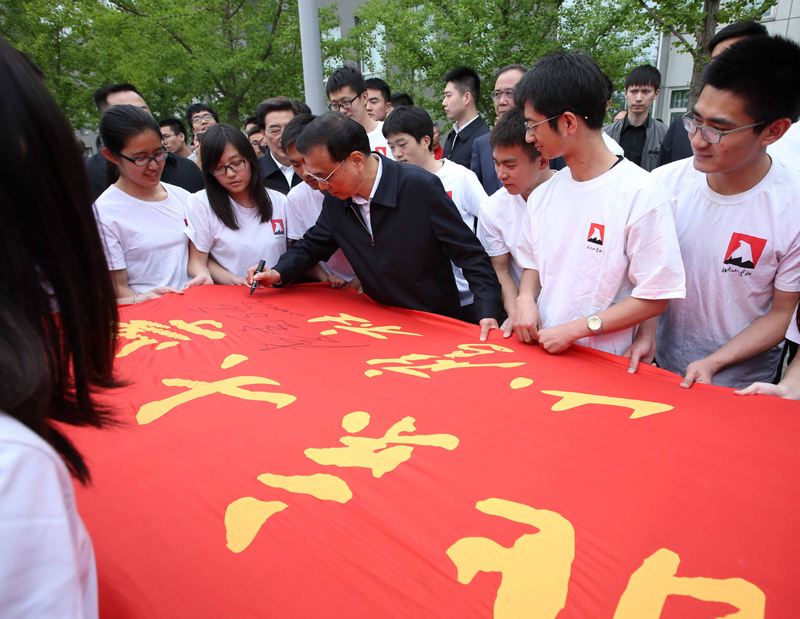 4月15日，李克强来到北京大学考察，应邀在山鹰社社旗上签名。